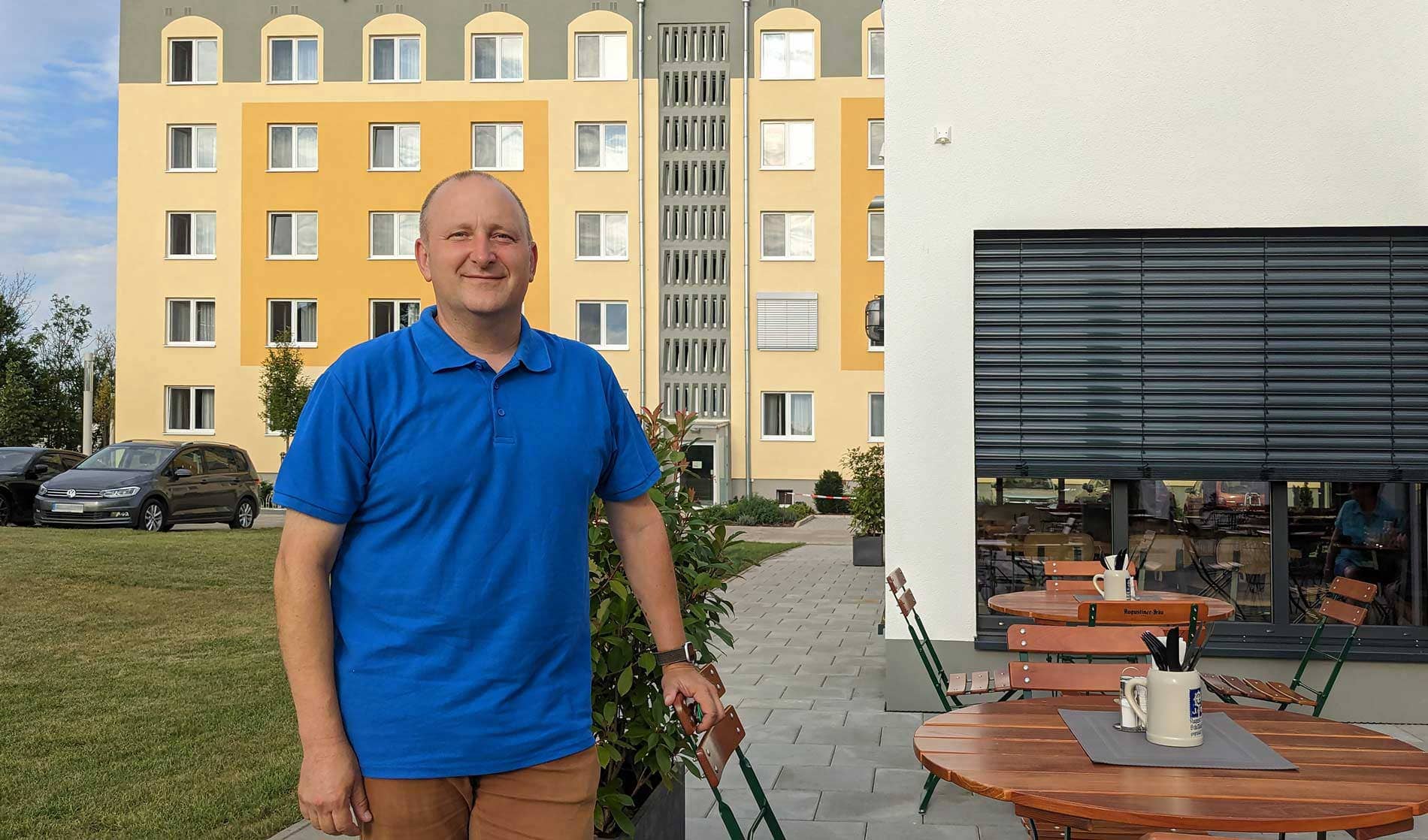 Portraitfoto von Matthias Golze, dem Hotelmanagers des Hotels Elbebrücke, der vor dem Restaurant posiert